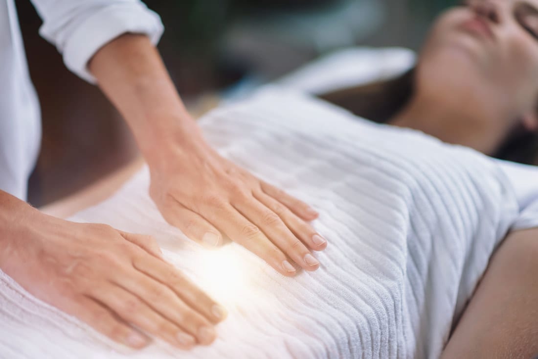Image of Nirvana Wellness Massage Therapist hands over pelvic region of woman with a warm glow